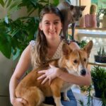 Dr. Pupich smiling with her corgi in her lap and cat on shoulder